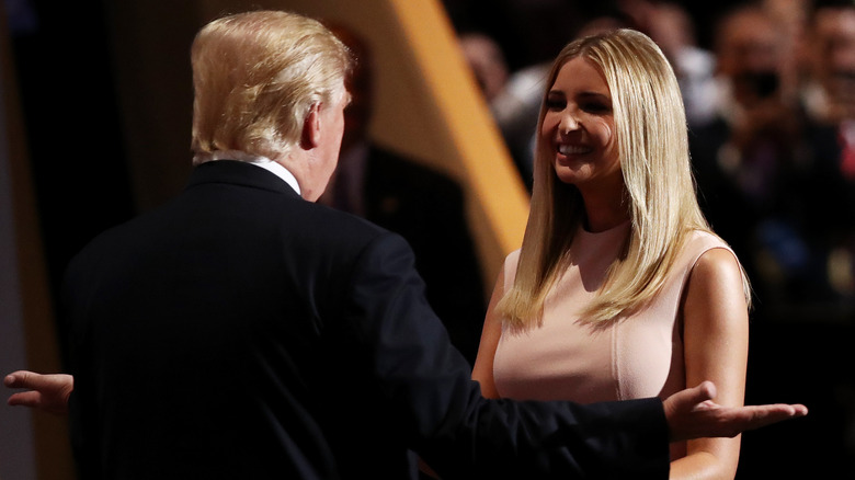 Donald Trump holding his arms out to a smiling Ivanka Trump