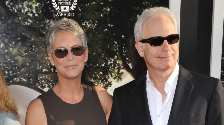 Jamie Lee Curtis and Christopher Guest smiling while wearing sunglasses