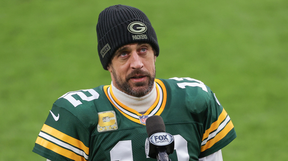 Aaron Rodgers wears a hat and football jersey