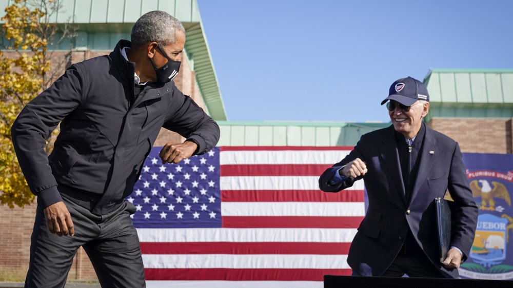 Barack Obama and Joe Biden both about to tap elbows in a greeting amid COVID-19