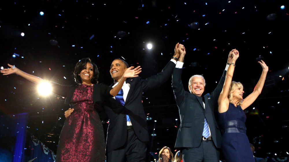 Michelle Obama, Barack Obama, Joe Biden, and Jill Biden all on stage with arms raised