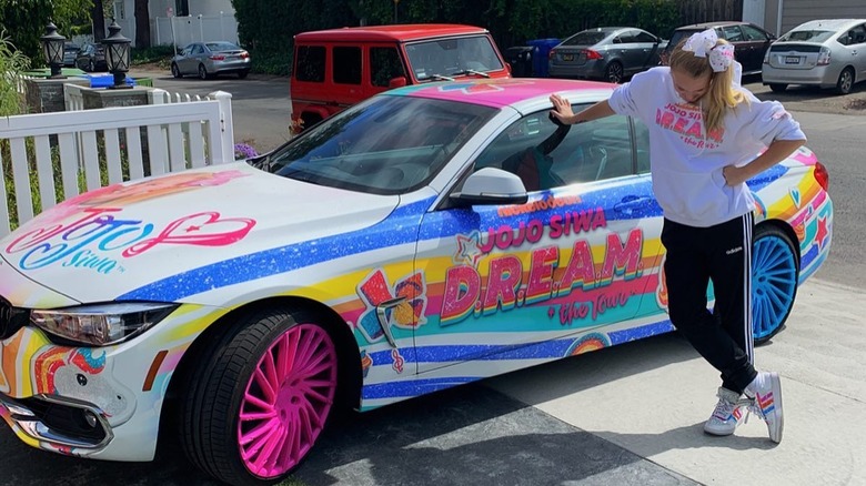 JoJo Siwa leaning against her colorful car