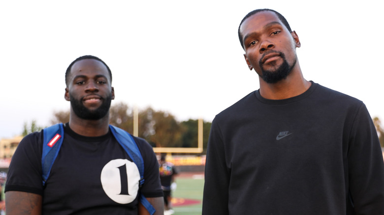 Draymond Green and Kevin Durant standing on a football field 