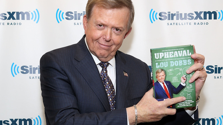 Lou Dobbs posing with his book