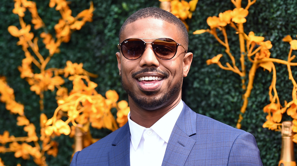 Michael B. Jordan in front of grassy, floral wall