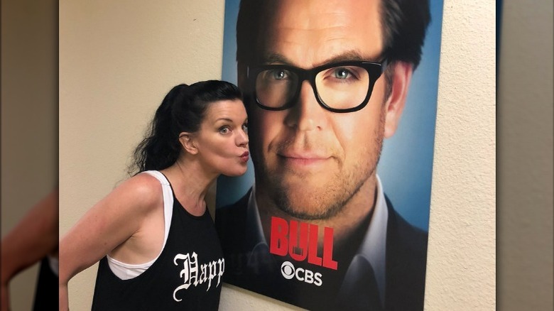 Pauley Perrette making kissy face beside 'Bull' poster