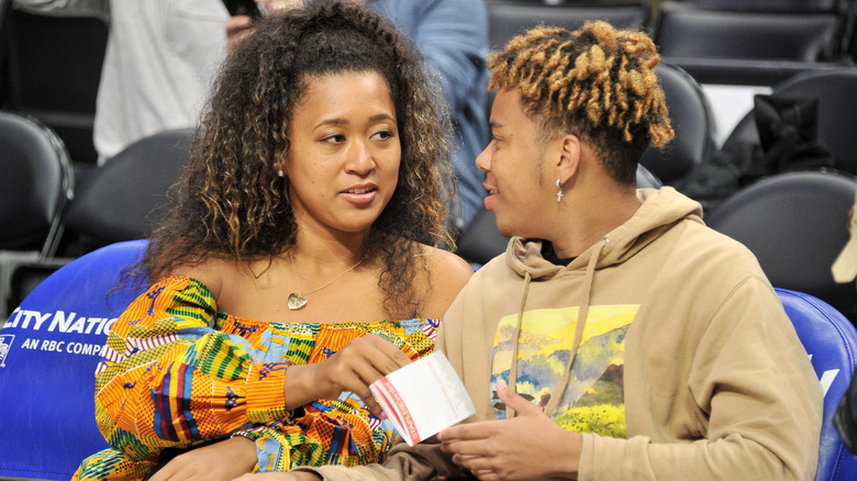 Naomi Osaka and Cordae smiling at Clippers game