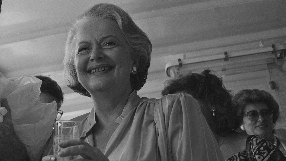 Black-and-white photo of Olivia de Havilland smiling and holding a drink