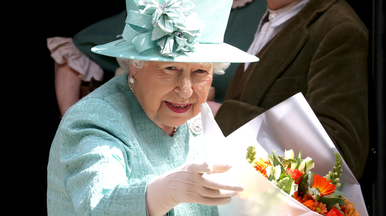 Queen Elizabeth in hat holding flowers