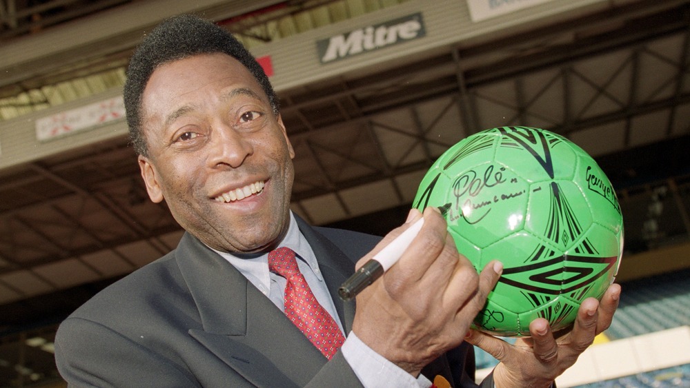 Pele signing autograph on a soccer ball