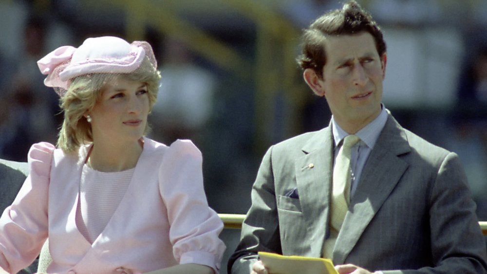 Princess Diana and Prince Charles, both looking off to the side with a grimace