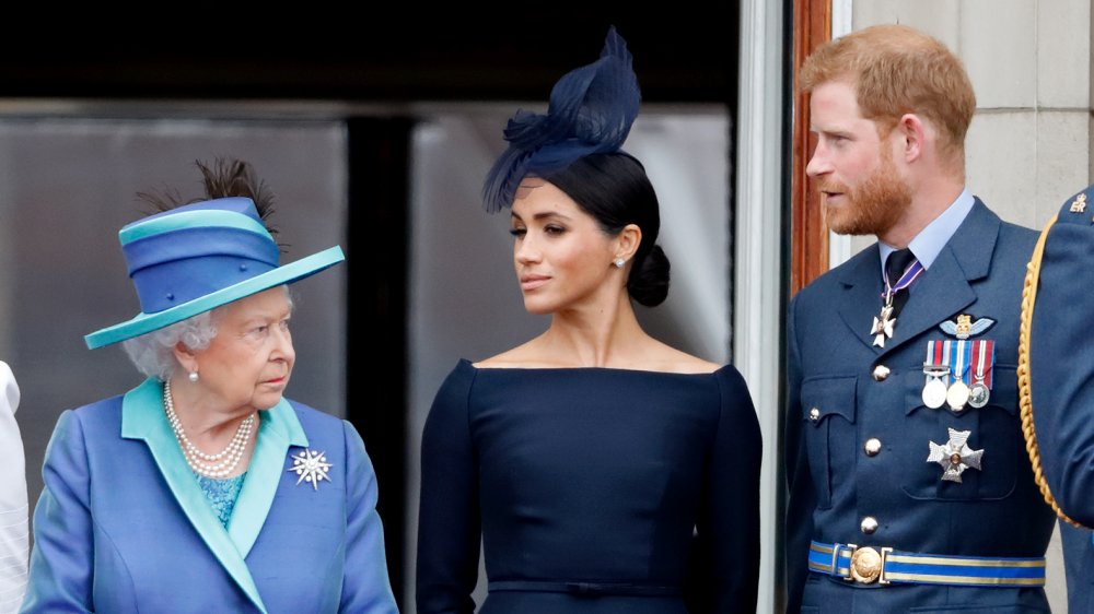 Queen Elizabeth, Meghan Markle, and Prince Harry atch a flypast to mark the centenary of the Royal Air Force from the balcony of Buckingham Palace in 2018