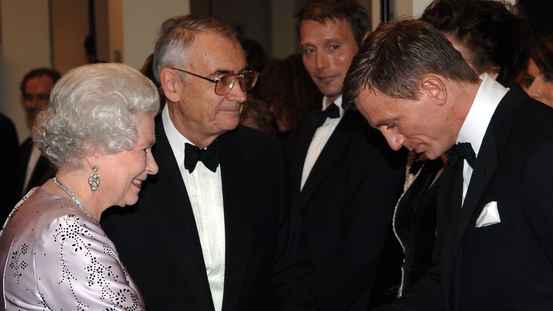 Queen Elizabeth smiles and gives Daniel Craig a handshake