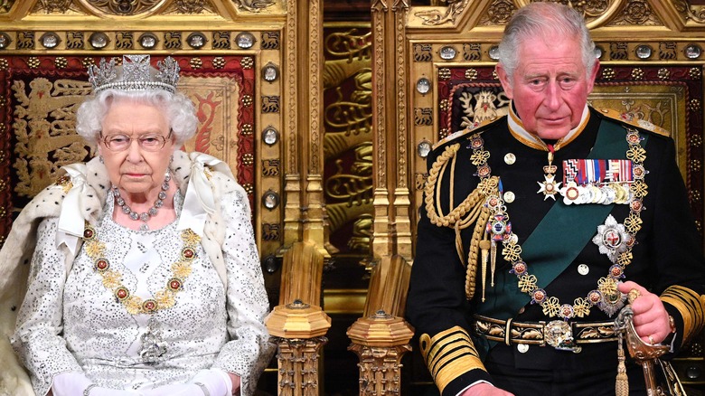 Queen Elizabeth II and King Charles III sitting on thrones