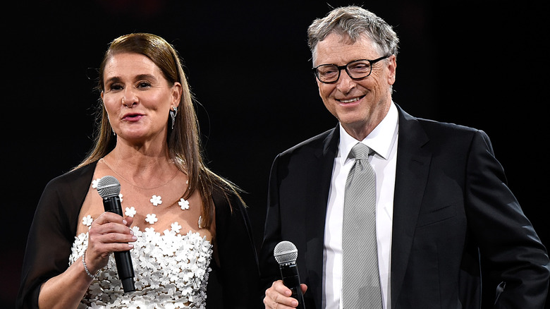 Melinda and Bill Gates speaking and smiling holding microphones