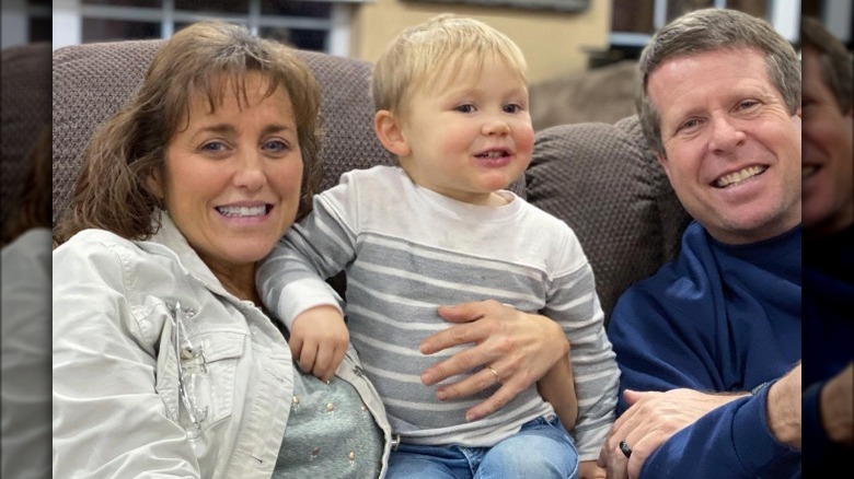 Michelle, Jim Bob Duggar on couch with child