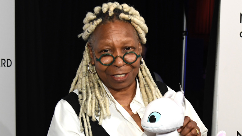 Whoopi Goldberg posing with a plush toy