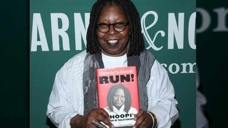 Whoopi Goldberg posing with her book