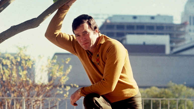 William Shatner posing next to a tree