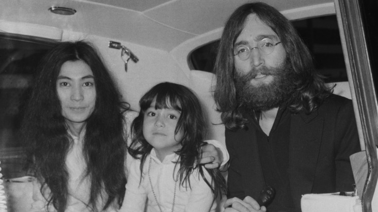 Yoko Ono, Kyoko Chan Cox as a child and John Lennon sitting together posing for the camera