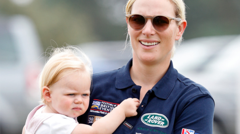 Zara Tindall carries her daughter at a polo event