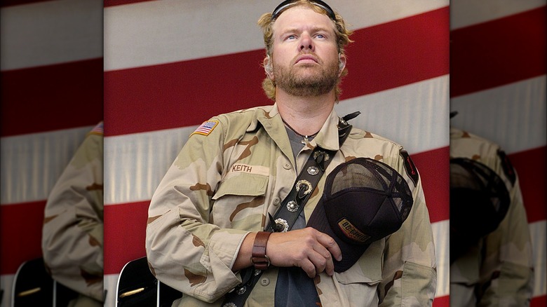 Toby Keith standing with hat over heart in front of American flag