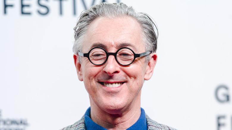 Alan Cumming smiling in glasses