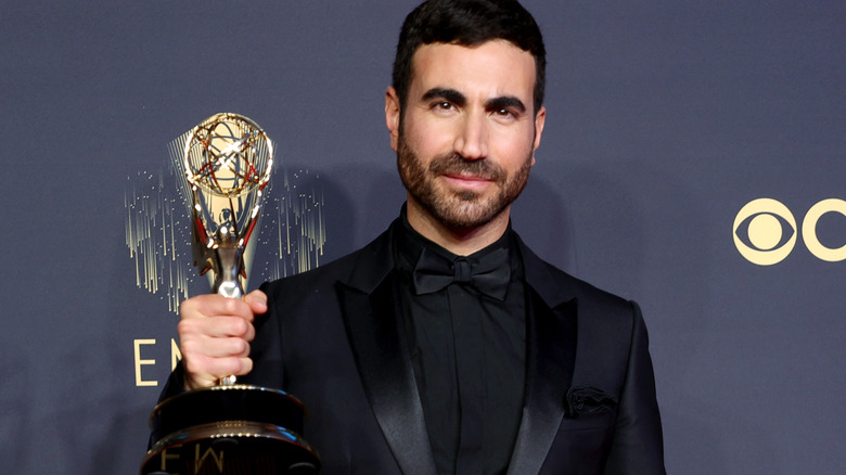 Brett Goldstein on red carpet, holding his Emmy and looking at camera