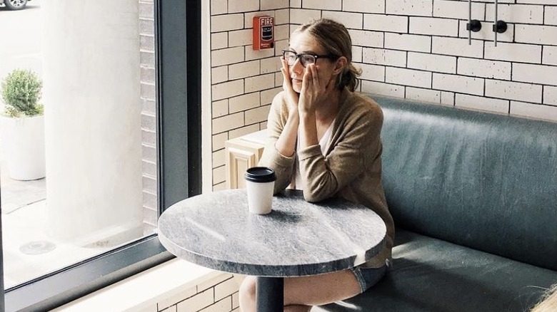 Caitlin Thompson, wearing glasses in a cafe