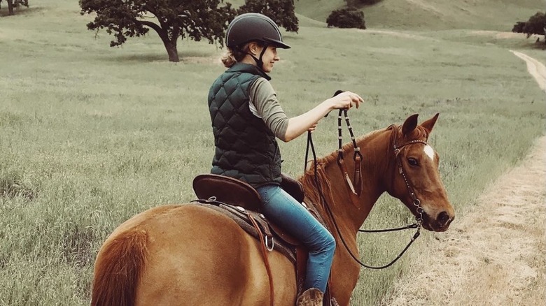 Caitlin Thompson, riding a horse in a field 