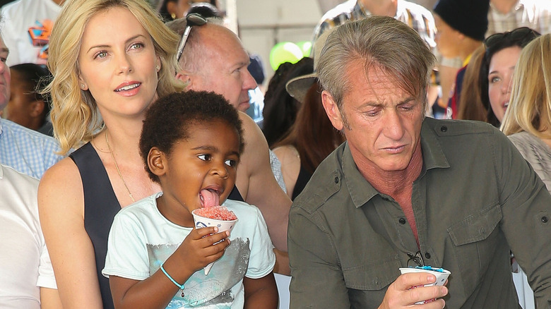 Charlize Theron with her child and Sean Penn, seated