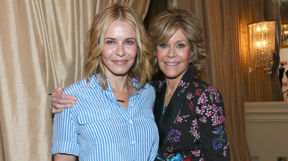 Chelsea Handler in a blue-and-white striped button-up shirt, Jane Fonda in a black, floral-printed blazer, posing at a Netflix luncheon in 2016