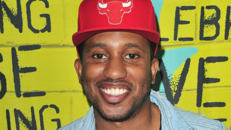 Chris Redd smiling in a red hat