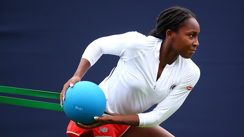 Coco Gauff exercising with a resistance band and blue ball