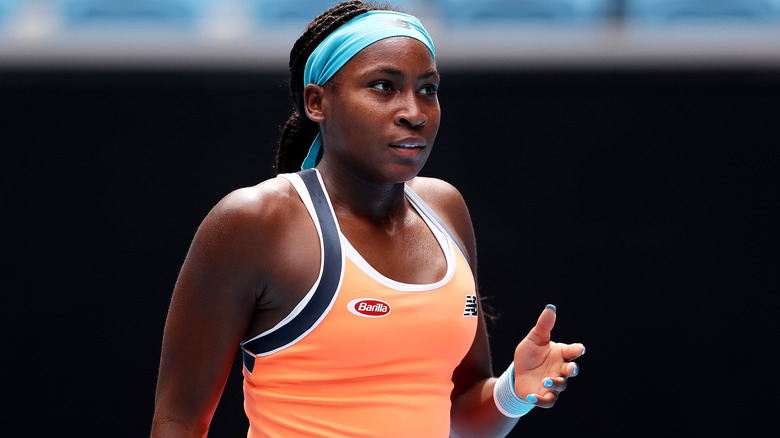 Coco Gauff wearing orange top and a light blue headband