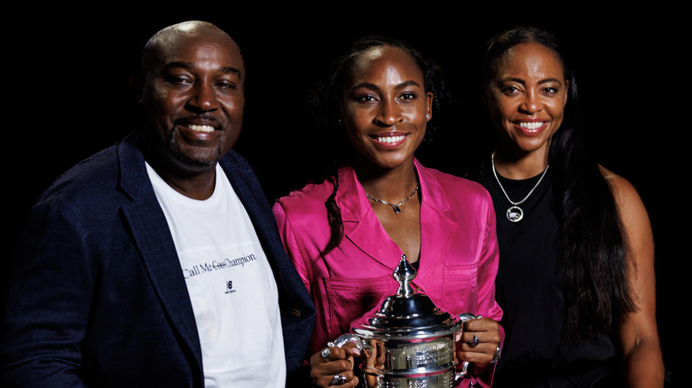 Corey, Coco, and Candi Gauff posing together with Coco holding her U.S. Open trophy