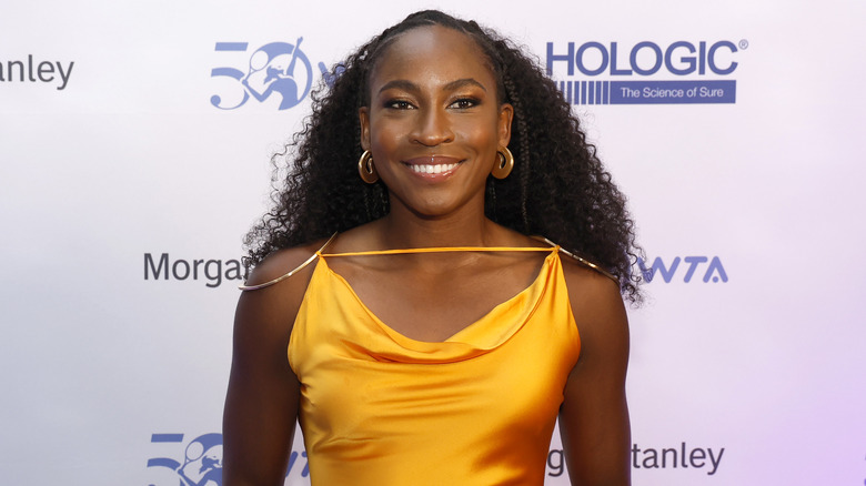 Coco Gauff smiling in a mustard dress