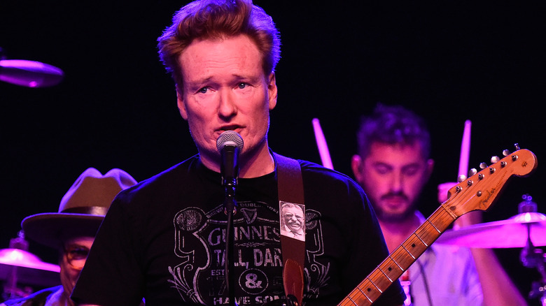 Conan O'Brien with a guitar on stage