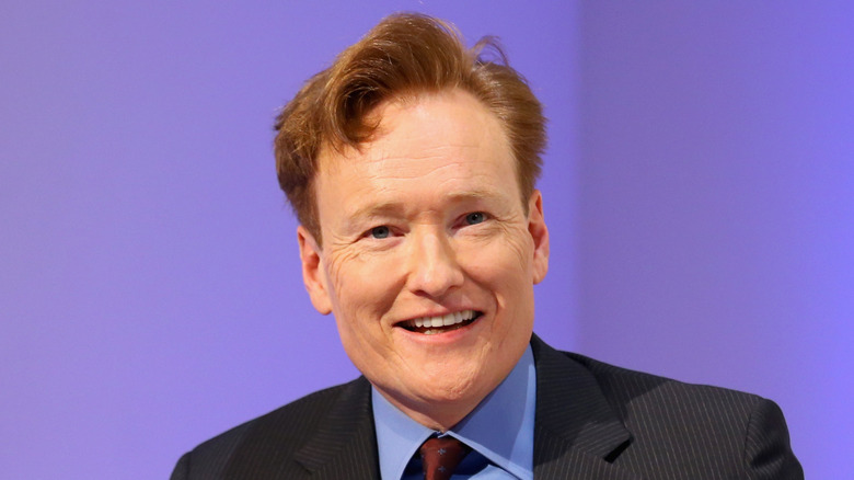 Conan O'Brien in a red tie, laughing