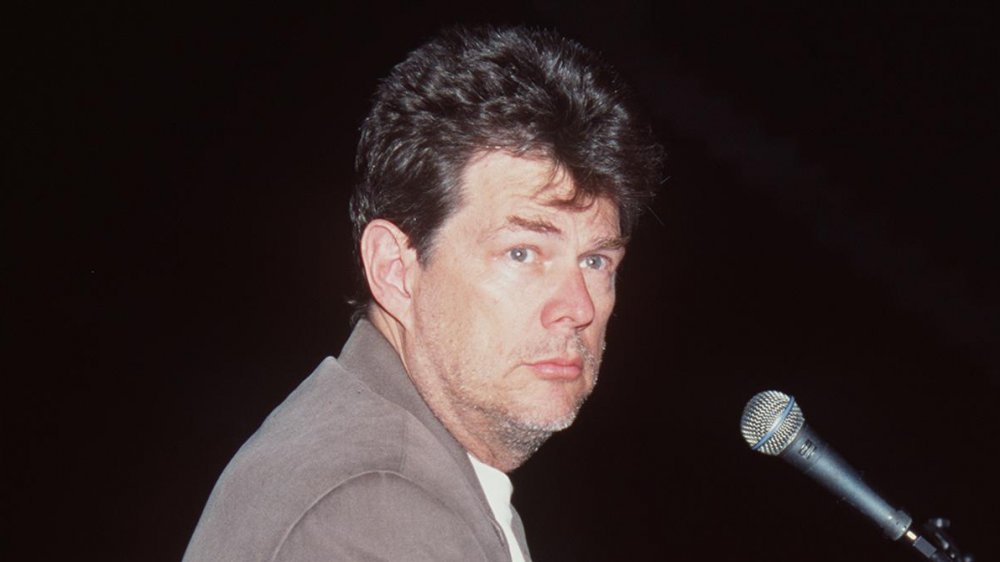 David Foster in a tan blazer, with a scruffy beard, sitting at a piano