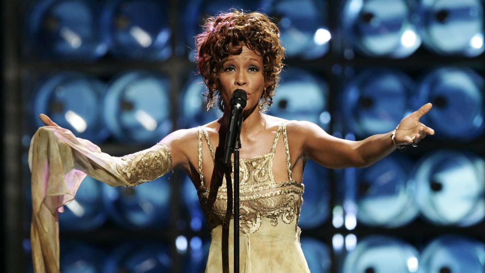 Whitney Houston singing live, wearing a gold dress