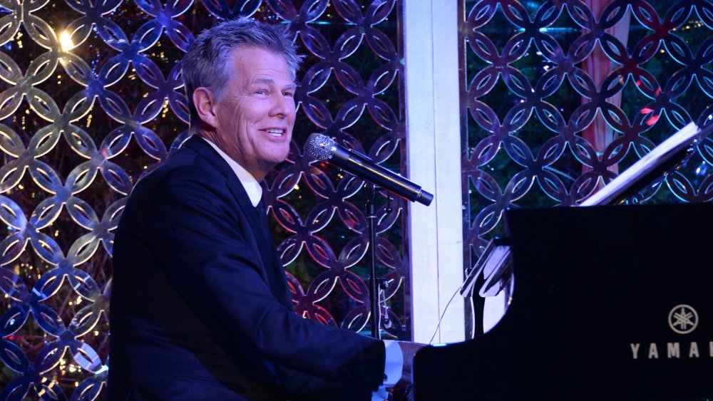 David Foster smiling while singing and playing piano