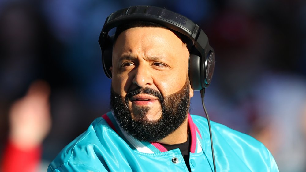 DJ Khaled with headphones on and blue bomber jacket