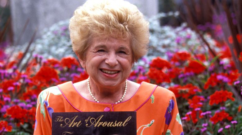 Dr Ruth smiling and holding her book