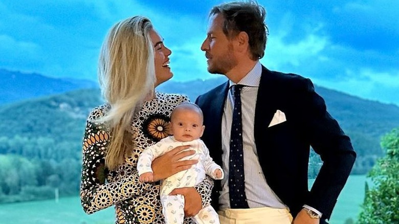 Will Kopelman and Alexandra Michler smiling and holding their baby