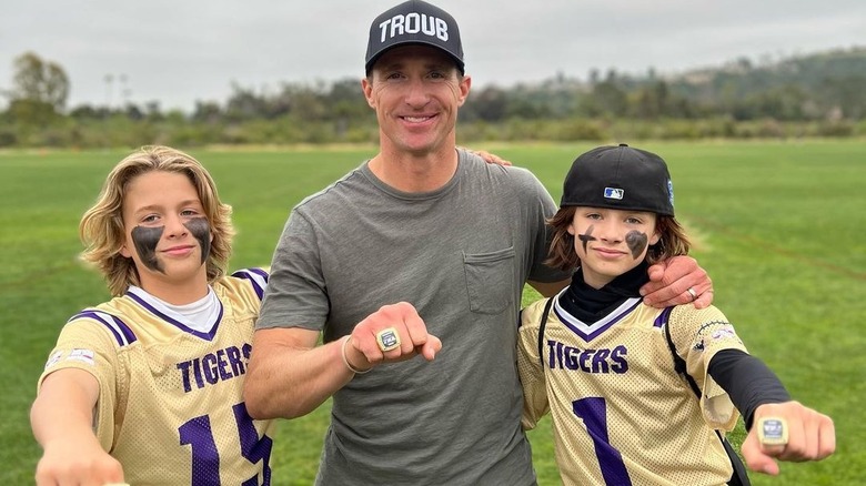 Drew Brees, posing with his sons on a football field