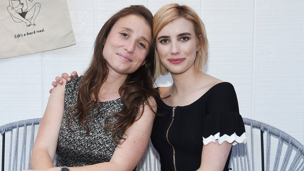 Karah Preiss and Emma Roberts sitting side-by-side with small smiles