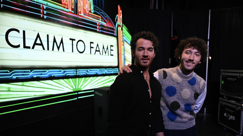 Kevin Jonas posing with Frankie Jonas next to sign for Claim to Fame