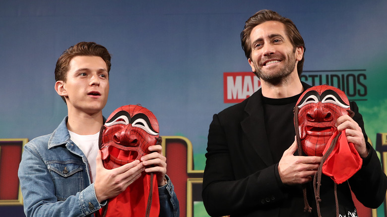 Tom Holland and Jake Gyllenhaal holding masks