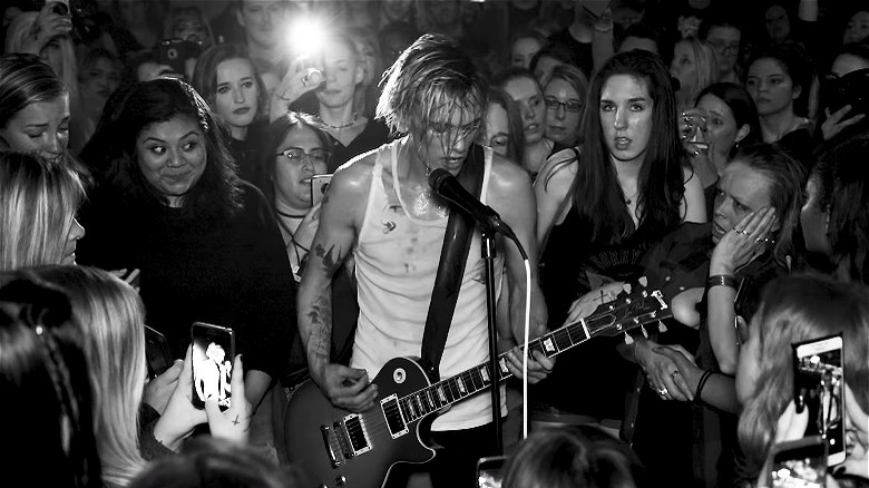 Jamie Campbell Bower playing music in a crowd